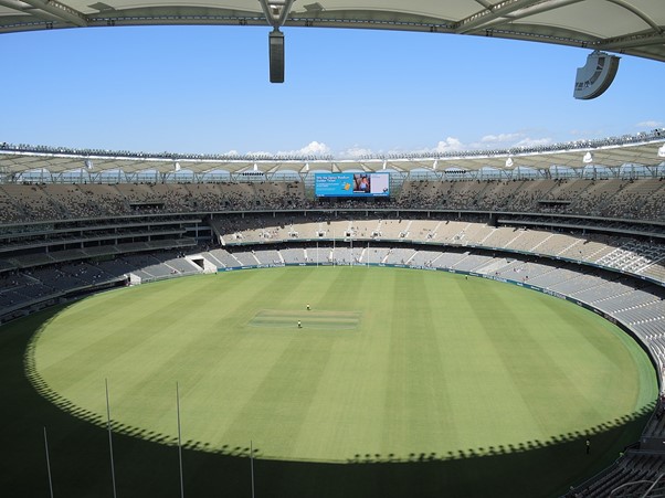 Half of a cricket ground with packed crowd and boundary rope